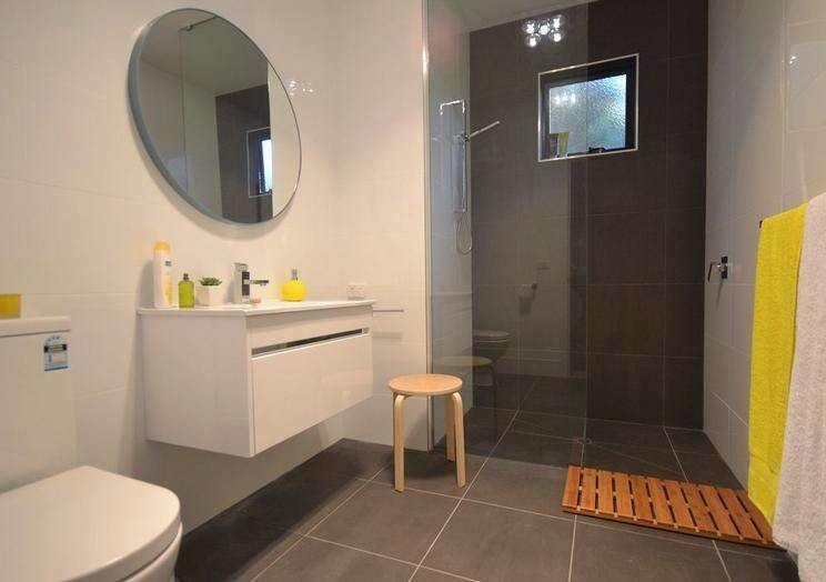 Mittelgroßes Modernes Badezimmer En Suite mit integriertem Waschbecken, weißen Schränken, Mineralwerkstoff-Waschtisch, bodengleicher Dusche, Wandtoilette mit Spülkasten, beigen Fliesen, weißer Wandfarbe und Keramikboden in Hobart