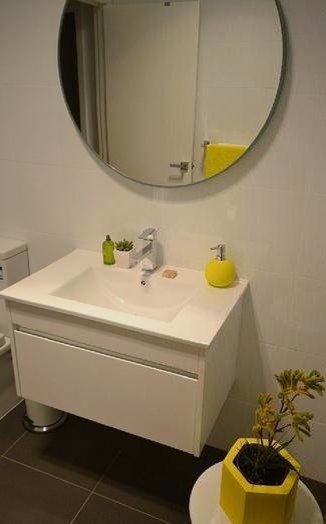 Bild på ett mellanstort funkis en-suite badrum, med ett integrerad handfat, vita skåp, bänkskiva i akrylsten, en kantlös dusch, beige kakel, vita väggar, klinkergolv i keramik och en toalettstol med separat cisternkåpa