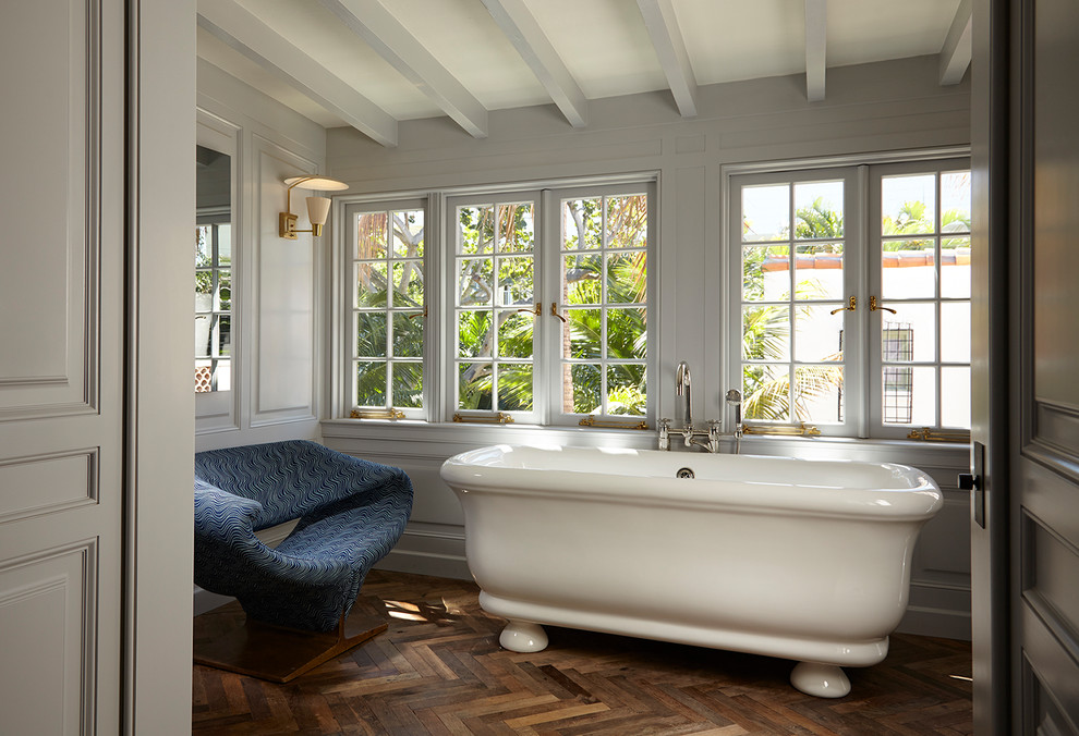 Ispirazione per una stanza da bagno mediterranea con vasca freestanding, pareti grigie, pavimento in legno massello medio e pavimento marrone