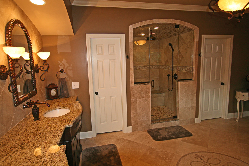 Example of a large classic master beige tile and stone tile travertine floor bathroom design in Atlanta with an undermount sink, furniture-like cabinets, dark wood cabinets, granite countertops, a two-piece toilet and brown walls