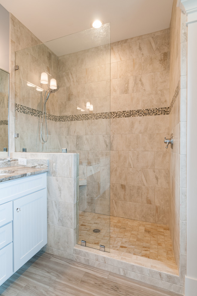 Amerikansk inredning av ett mycket stort en-suite badrum, med luckor med infälld panel, vita skåp, ett fristående badkar, en dusch i en alkov, en toalettstol med separat cisternkåpa, flerfärgad kakel, marmorkakel, bruna väggar, ljust trägolv, ett undermonterad handfat, granitbänkskiva, flerfärgat golv och dusch med gångjärnsdörr