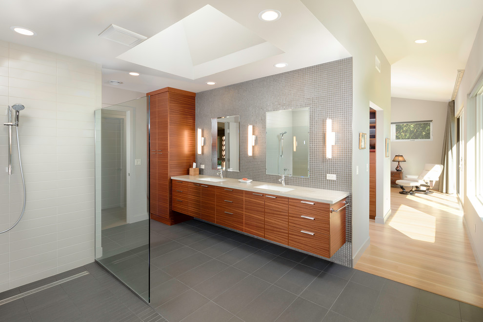 Modernes Badezimmer mit Kassettenfronten, dunklen Holzschränken, bodengleicher Dusche, grauen Fliesen, Mosaikfliesen, Unterbauwaschbecken, grauem Boden, offener Dusche und beiger Waschtischplatte in Seattle