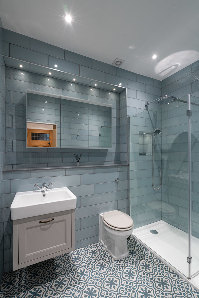 Diseño de cuarto de baño azulejo de dos tonos clásico renovado con armarios con paneles empotrados, puertas de armario beige, ducha esquinera, sanitario de una pieza, baldosas y/o azulejos azules, aseo y ducha, lavabo suspendido y suelo multicolor