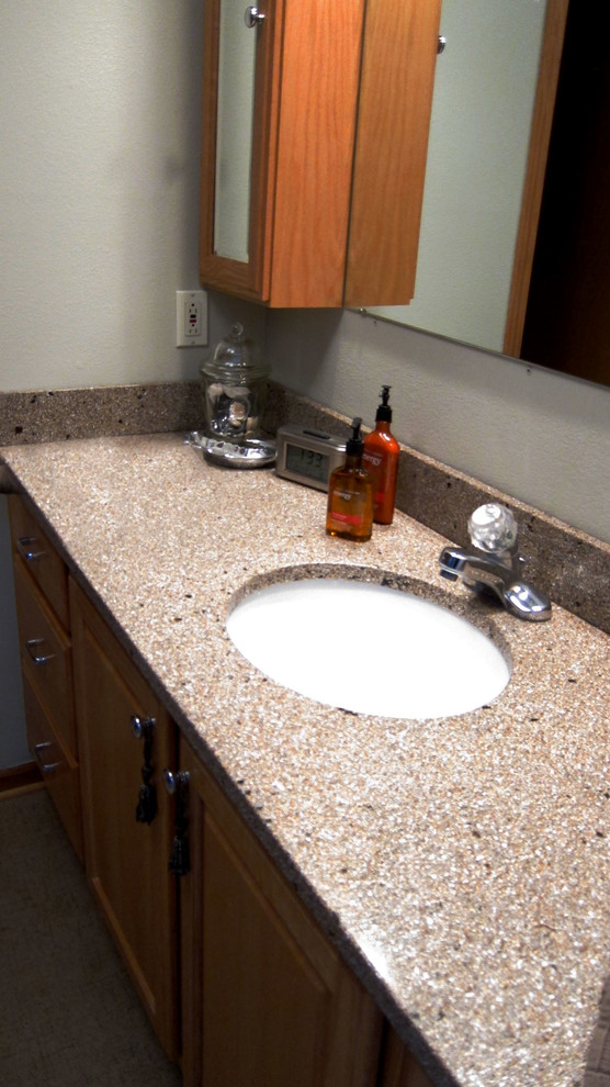 Réalisation d'une salle de bain principale bohème en bois brun de taille moyenne avec un lavabo encastré, un placard avec porte à panneau surélevé, un plan de toilette en granite, un mur gris et un sol en linoléum.
