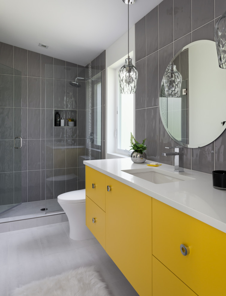 Aménagement d'une salle de bain grise et jaune contemporaine avec un placard à porte plane, des portes de placard jaunes, un carrelage gris, un lavabo encastré, un sol gris, une cabine de douche à porte battante, un plan de toilette blanc, meuble simple vasque, meuble-lavabo suspendu et un plafond voûté.
