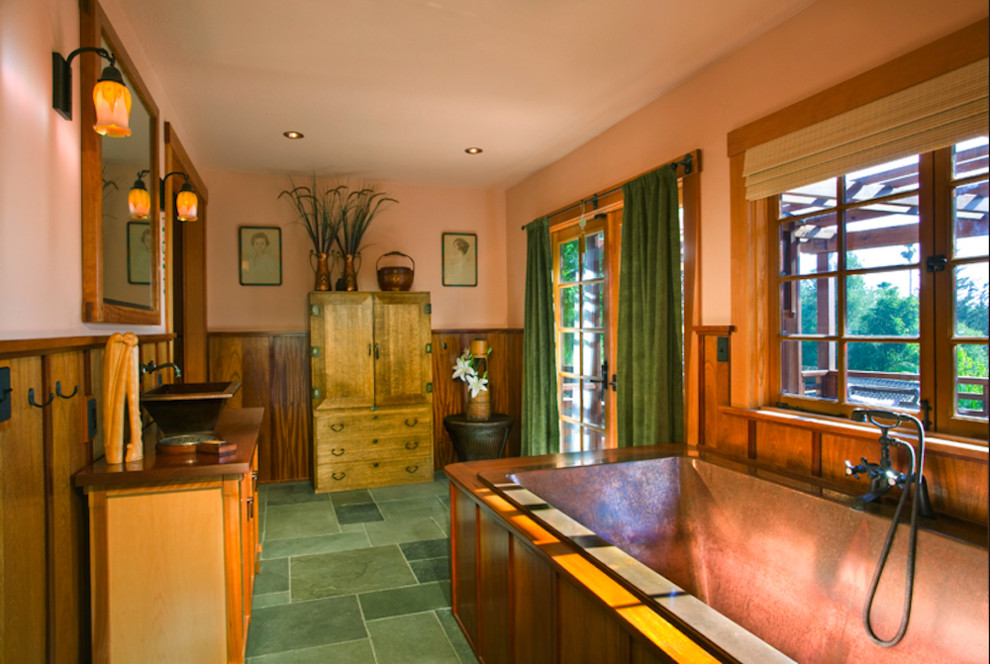 На фото: главная ванная комната среднего размера в восточном стиле с консольной раковиной, светлыми деревянными фасадами, столешницей из дерева, отдельно стоящей ванной, зеленой плиткой, коричневыми стенами и полом из керамической плитки с