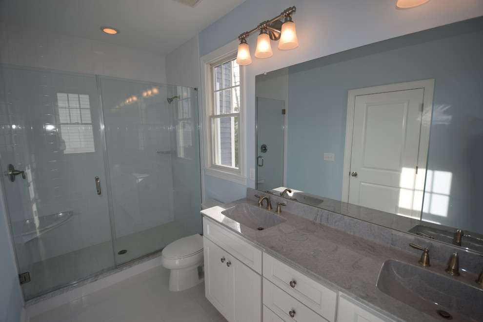Cette photo montre une salle de bain bord de mer avec un placard avec porte à panneau encastré, des portes de placard blanches, un mur bleu et un lavabo intégré.