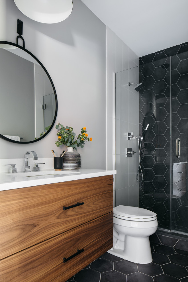 Foto på ett funkis vit badrum, med släta luckor, skåp i mellenmörkt trä, en dusch i en alkov, grå väggar, ett undermonterad handfat, svart golv och dusch med gångjärnsdörr