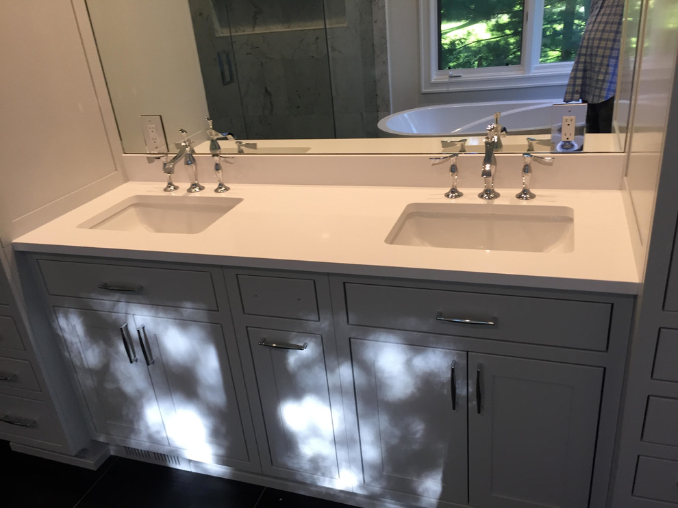 Mid-sized elegant master ceramic tile and gray floor bathroom photo in Detroit with shaker cabinets, gray cabinets, white walls, an undermount sink and solid surface countertops