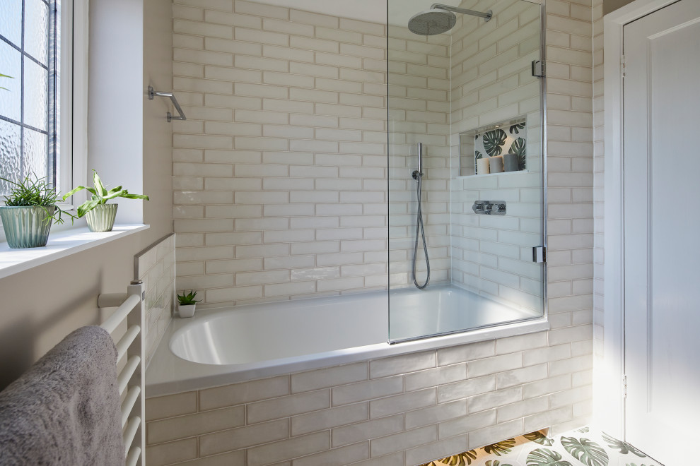 На фото: детская ванная комната в стиле неоклассика (современная классика) с накладной ванной, душем над ванной, раздельным унитазом, белой плиткой, керамической плиткой, бежевыми стенами, полом из керамической плитки, подвесной раковиной, столешницей из искусственного камня, разноцветным полом, душем с распашными дверями, белой столешницей и подвесной тумбой с
