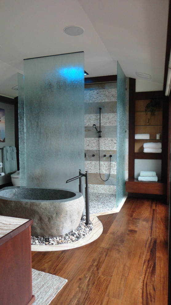 Modern inredning av ett stort en-suite badrum, med ett fristående handfat, möbel-liknande, skåp i mellenmörkt trä, bänkskiva i onyx, ett fristående badkar, en dubbeldusch, en toalettstol med hel cisternkåpa, mellanmörkt trägolv, brunt golv och med dusch som är öppen