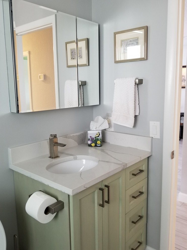 Photo of a small beach style family bathroom in Miami with shaker cabinets, green cabinets, an alcove shower, a one-piece toilet, green tiles, metro tiles, grey walls, porcelain flooring, a submerged sink, quartz worktops, grey floors, a sliding door and white worktops.