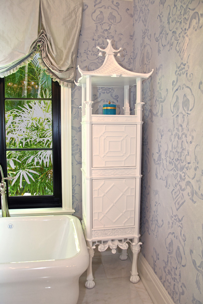 Cette image montre une salle de bain principale asiatique avec des portes de placard blanches, une baignoire indépendante, WC à poser, un carrelage blanc, un mur bleu et un sol en marbre.