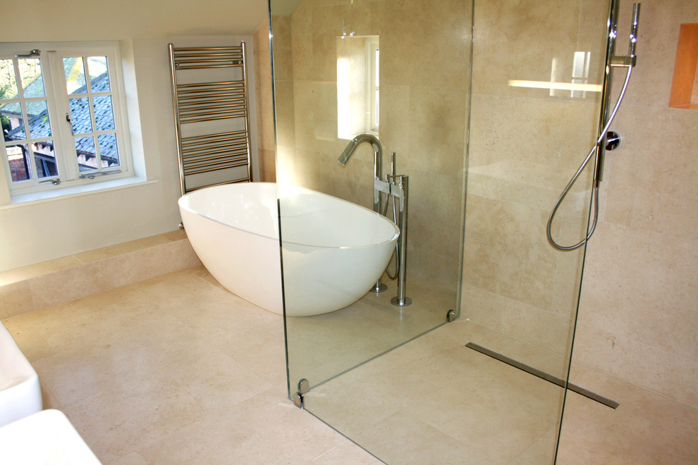 Modern inredning av ett mellanstort en-suite badrum, med ett fristående badkar, en hörndusch, en toalettstol med separat cisternkåpa, beige kakel, stenkakel, vita väggar och kalkstensgolv