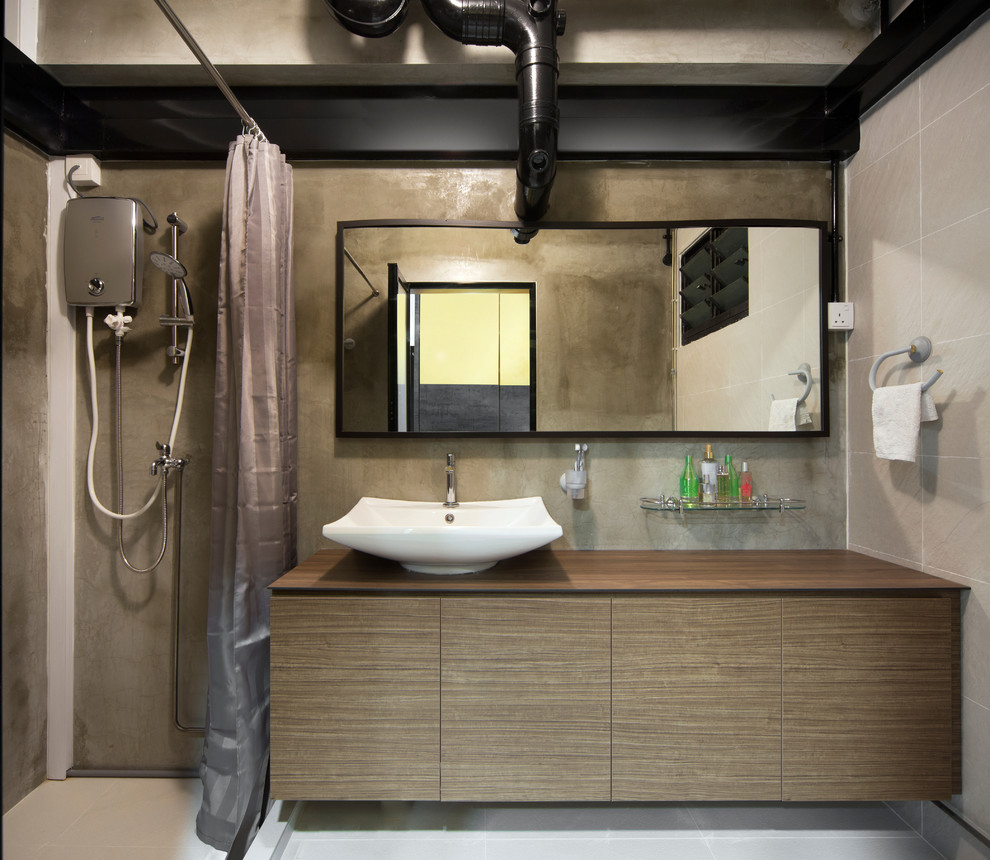 Diseño de cuarto de baño industrial con armarios con paneles lisos, puertas de armario de madera oscura, ducha esquinera, paredes grises, lavabo sobreencimera y encimera de madera