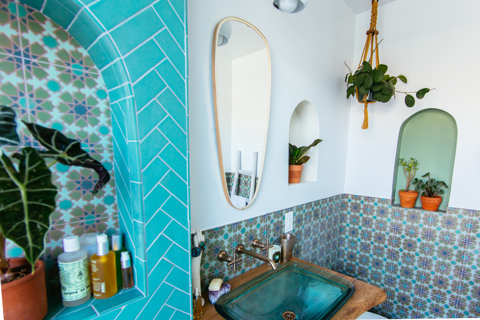 Immagine di una stanza da bagno mediterranea con vasca/doccia, piastrelle verdi, piastrelle in ceramica, pareti bianche, pavimento con piastrelle in ceramica, lavabo a colonna, top in legno, pavimento verde e doccia aperta