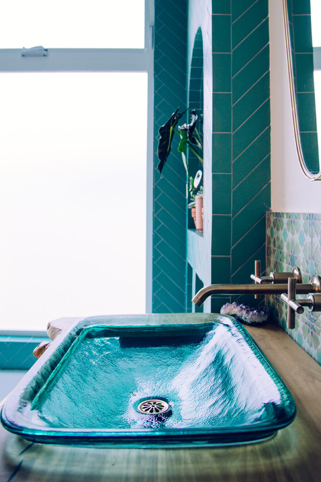 На фото: ванная комната в средиземноморском стиле с душем над ванной, зеленой плиткой, керамической плиткой, белыми стенами, полом из керамической плитки, раковиной с пьедесталом, столешницей из дерева, зеленым полом и открытым душем с