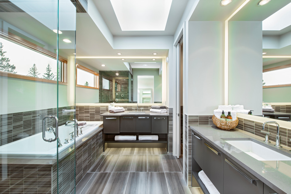 Modern inredning av ett grå grått badrum, med ett undermonterad handfat, släta luckor, grå skåp, ett platsbyggt badkar, en hörndusch, grå kakel, mosaik och blå väggar