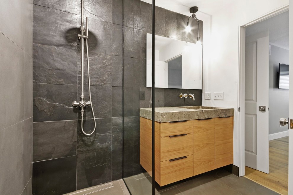 Mid-sized trendy master gray tile and slate tile porcelain tile and gray floor alcove shower photo in Cleveland with flat-panel cabinets, light wood cabinets, gray walls, an integrated sink, marble countertops, a hinged shower door and gray countertops