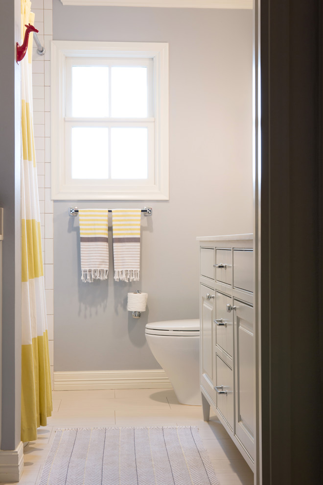 Exempel på ett mellanstort klassiskt badrum för barn, med ett undermonterad handfat, luckor med profilerade fronter, grå skåp, bänkskiva i akrylsten, ett badkar i en alkov, en toalettstol med hel cisternkåpa, vit kakel, tunnelbanekakel, grå väggar och klinkergolv i porslin