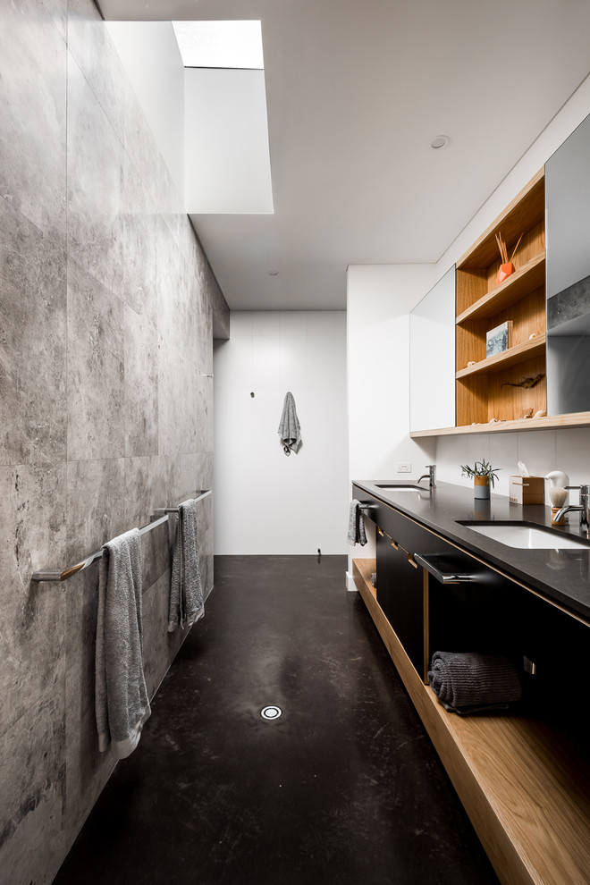 Immagine di una stanza da bagno padronale minimalista con ante lisce, ante nere, pareti bianche, pavimento in cemento, lavabo sottopiano, pavimento nero e top nero