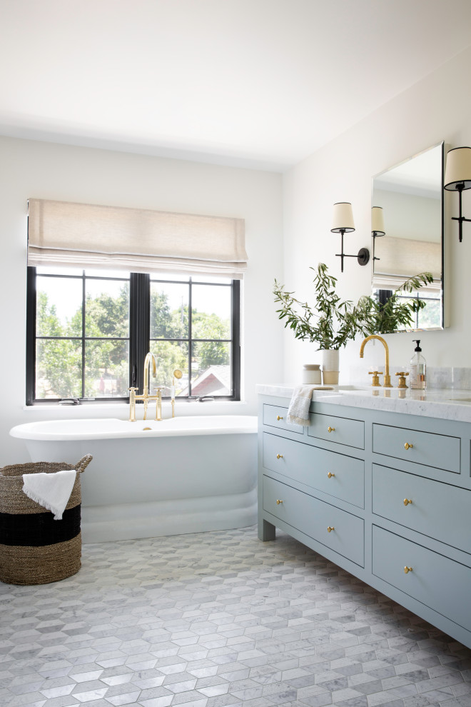 Beach style ensuite bathroom in San Francisco with blue cabinets, a freestanding bath, white walls, a submerged sink, grey floors, white worktops, double sinks, a freestanding vanity unit and flat-panel cabinets.