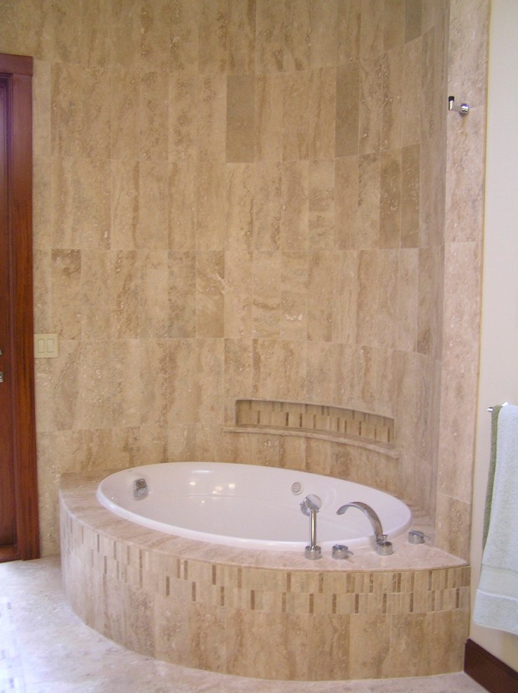 Ejemplo de cuarto de baño principal exótico de tamaño medio con armarios tipo mueble, puertas de armario de madera clara, encimera de granito, bañera encastrada, baldosas y/o azulejos beige, baldosas y/o azulejos en mosaico y suelo de travertino