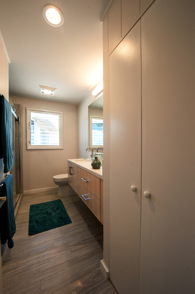 Ejemplo de cuarto de baño tradicional renovado con lavabo bajoencimera, armarios con paneles lisos, puertas de armario de madera clara, encimera de cuarcita, sanitario de dos piezas, baldosas y/o azulejos de vidrio y paredes blancas