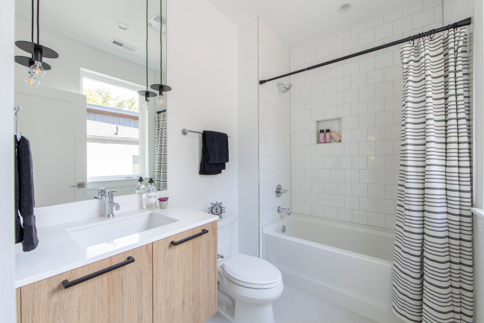 Ejemplo de cuarto de baño actual con armarios con paneles lisos, puertas de armario de madera clara, combinación de ducha y bañera, lavabo sobreencimera, encimera de cuarzo compacto, ducha con cortina y encimeras blancas