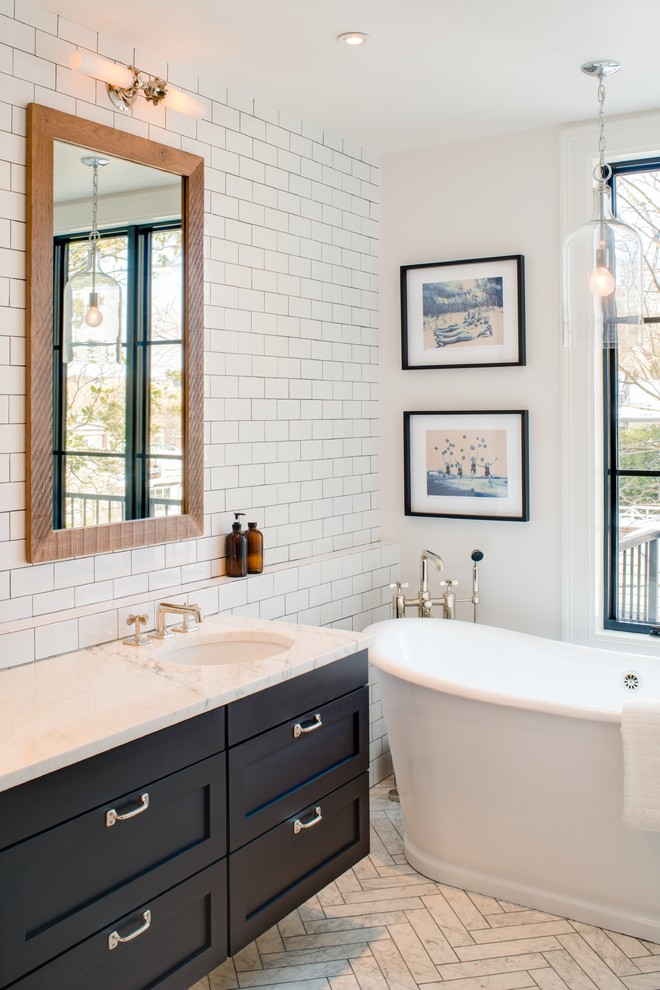 Exemple d'une salle de bain chic avec un lavabo encastré, un placard à porte shaker, des portes de placard noires, un plan de toilette en marbre, une baignoire indépendante, un carrelage blanc, des carreaux de porcelaine, un mur blanc et un sol en marbre.