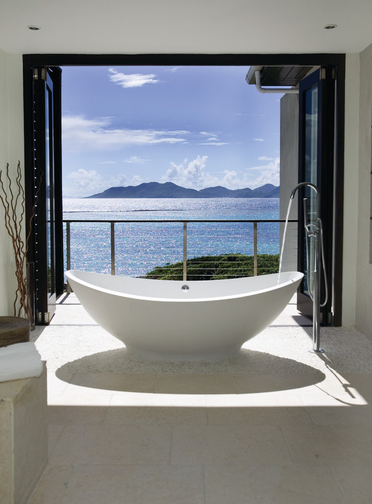 На фото: большая главная ванная комната в морском стиле с отдельно стоящей ванной, бежевой плиткой, белыми стенами и полом из галечной плитки с