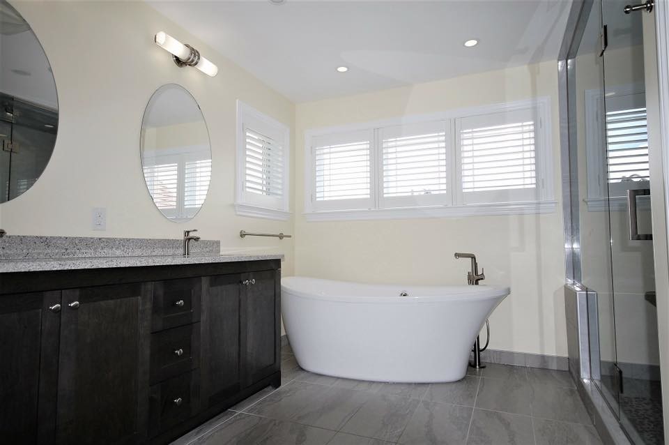 Klassisk inredning av ett stort grå grått en-suite badrum, med skåp i shakerstil, skåp i mörkt trä, ett fristående badkar, en dusch i en alkov, en toalettstol med separat cisternkåpa, grå kakel, porslinskakel, gula väggar, klinkergolv i porslin, ett undermonterad handfat, bänkskiva i kvarts, grått golv och dusch med gångjärnsdörr