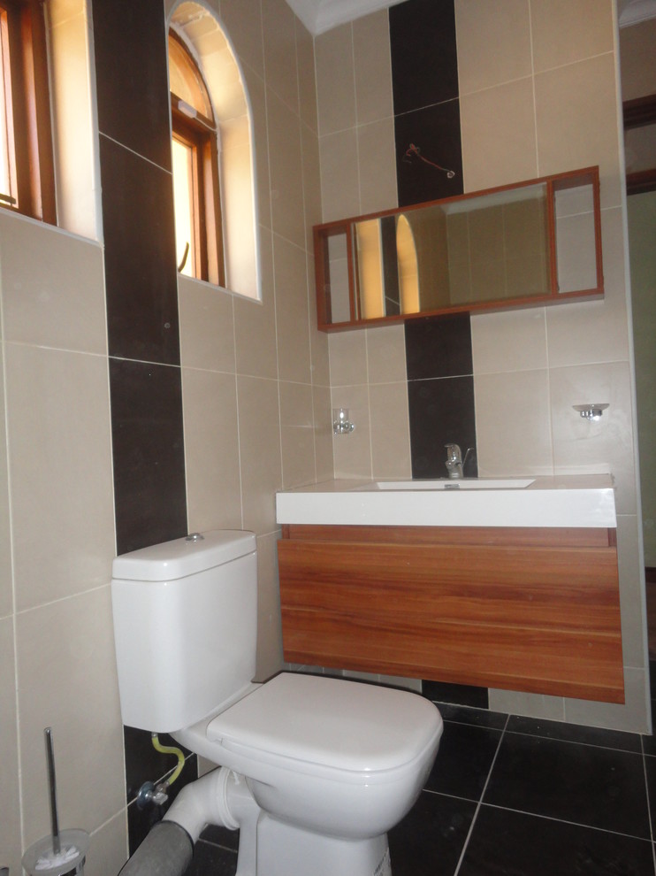 Photo of a medium sized modern family bathroom in Other with a console sink, flat-panel cabinets, light wood cabinets, limestone worktops, a claw-foot bath, a shower/bath combination, a one-piece toilet, brown tiles, porcelain tiles, beige walls and porcelain flooring.