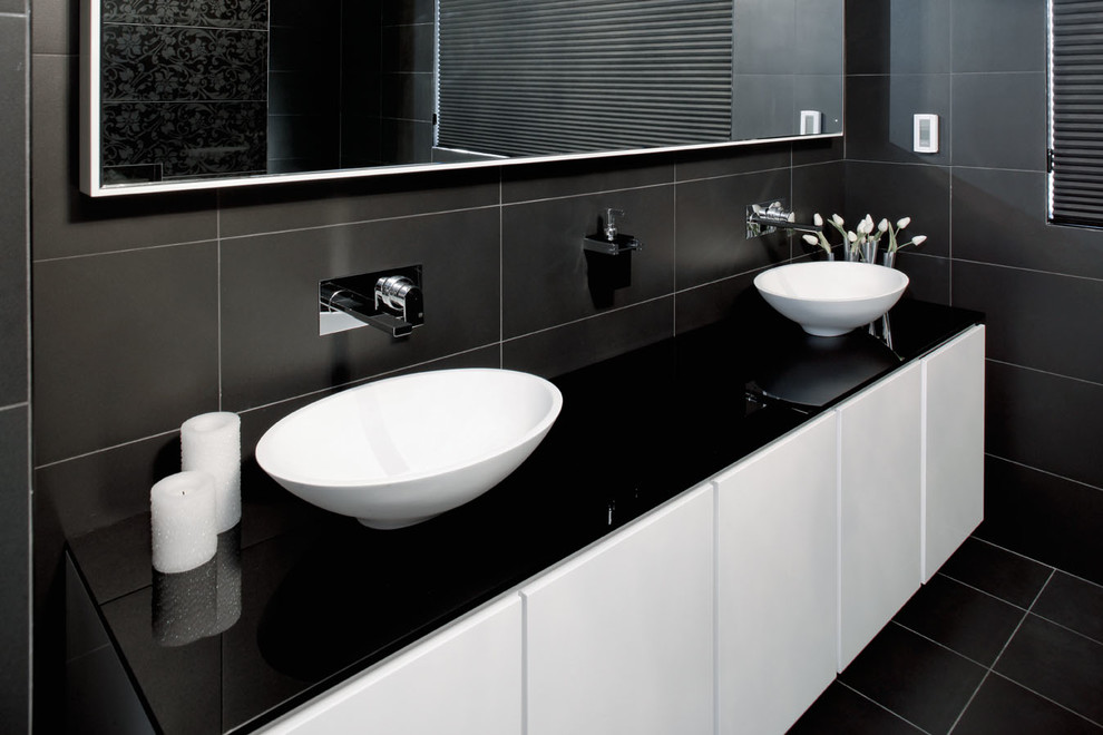 Пример оригинального дизайна: большая главная ванная комната в стиле модернизм с белыми фасадами, стеклянной столешницей, отдельно стоящей ванной, открытым душем, инсталляцией, черной плиткой, керамической плиткой, черными стенами и полом из керамической плитки
