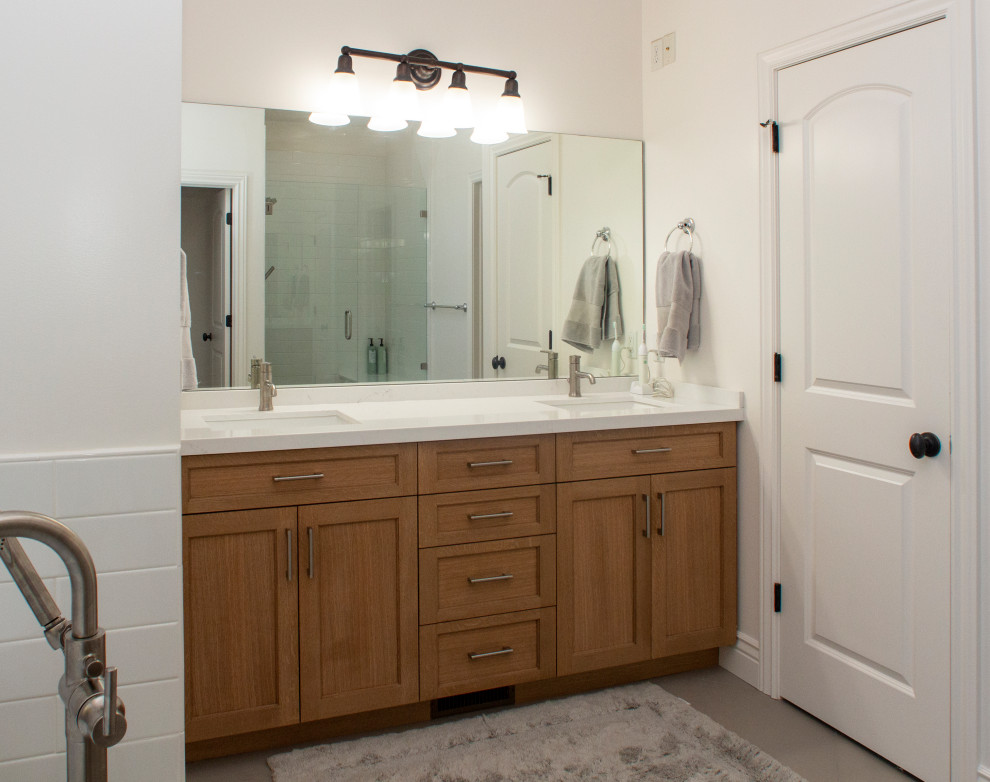Klassisk inredning av ett stort vit vitt en-suite badrum, med skåp i shakerstil, skåp i ljust trä, ett fristående badkar, en hörndusch, vit kakel, tunnelbanekakel, vita väggar, klinkergolv i keramik, ett undermonterad handfat, bänkskiva i kvarts, grått golv och dusch med gångjärnsdörr