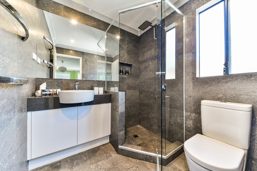 Свежая идея для дизайна: ванная комната в современном стиле с плоскими фасадами, белыми фасадами, угловым душем, раздельным унитазом, серой плиткой, серыми стенами, настольной раковиной и душем с распашными дверями - отличное фото интерьера
