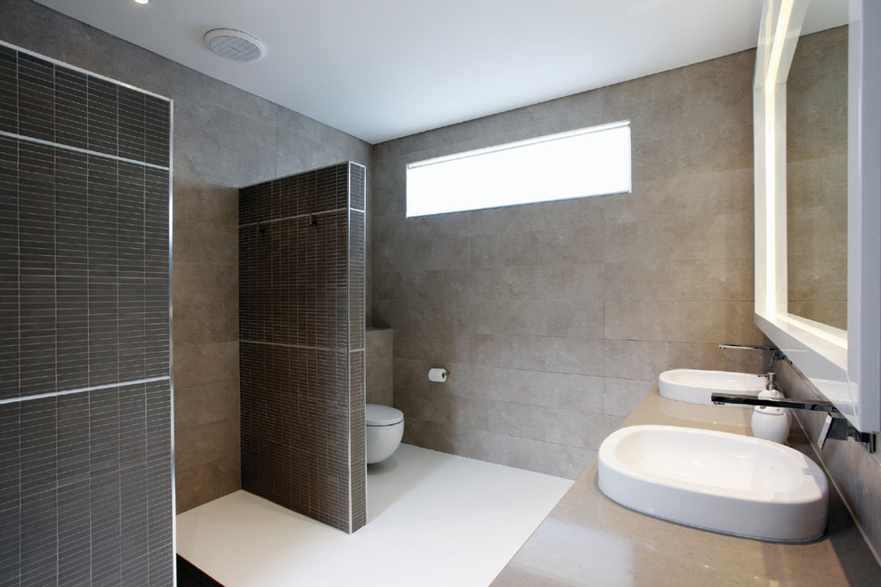 Foto de cuarto de baño contemporáneo de tamaño medio con lavabo sobreencimera, encimera de cuarzo compacto, ducha abierta, sanitario de pared, baldosas y/o azulejos marrones y paredes marrones