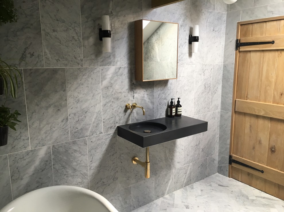 This is an example of a large contemporary ensuite bathroom in New York with a freestanding bath, grey tiles, marble tiles, grey walls, marble flooring, a wall-mounted sink, concrete worktops and grey floors.