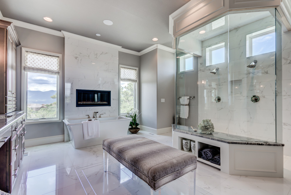 Klassisk inredning av ett stort en-suite badrum, med luckor med upphöjd panel, skåp i ljust trä, ett fristående badkar, en kantlös dusch, en toalettstol med separat cisternkåpa, vit kakel, porslinskakel, grå väggar, klinkergolv i porslin, ett undermonterad handfat, marmorbänkskiva, vitt golv och med dusch som är öppen