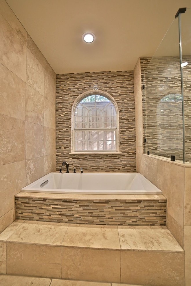 Large traditional ensuite bathroom in Dallas with a submerged sink, shaker cabinets, light wood cabinets, solid surface worktops, a built-in bath, a walk-in shower, a two-piece toilet, beige tiles, glass tiles, beige walls and travertine flooring.