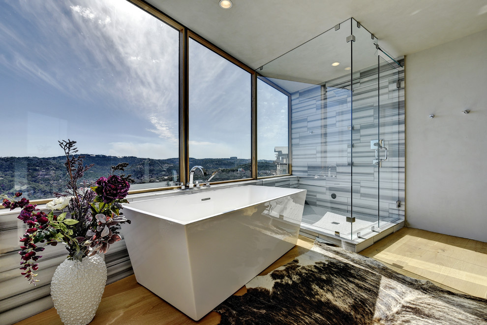 Modernes Badezimmer mit freistehender Badewanne, Eckdusche, grauer Wandfarbe und hellem Holzboden in Austin