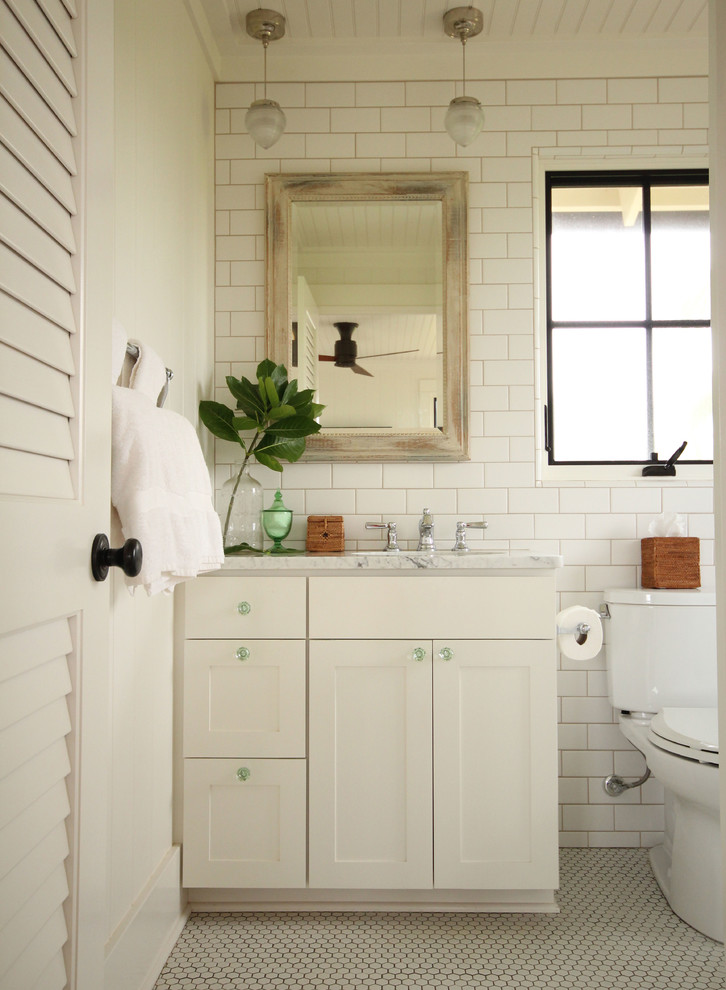Foto på ett litet maritimt badrum med dusch, med skåp i shakerstil, vita skåp, marmorbänkskiva, vit kakel, tunnelbanekakel, ett undermonterad handfat, en toalettstol med separat cisternkåpa, vita väggar och mosaikgolv
