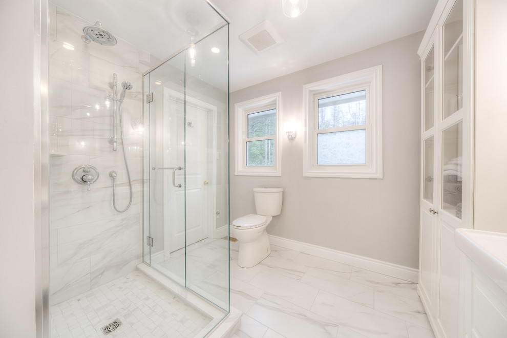Example of a mid-sized transitional 3/4 white tile and porcelain tile porcelain tile and white floor corner shower design in Toronto with raised-panel cabinets, white cabinets, a two-piece toilet, gray walls, an integrated sink, solid surface countertops, a hinged shower door and white countertops