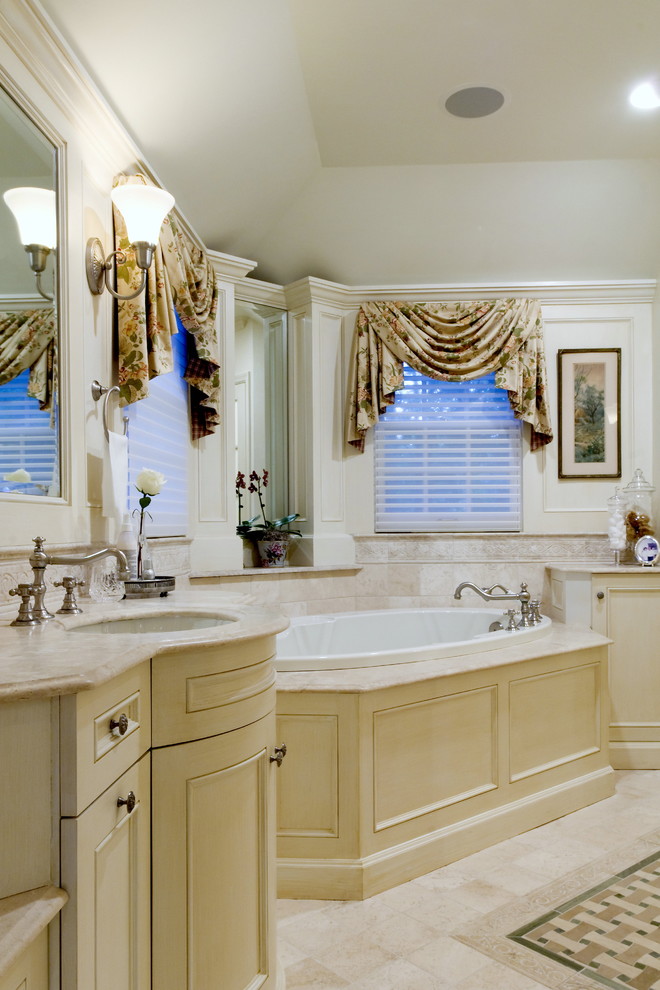 Idée de décoration pour une salle de bain tradition avec un lavabo encastré, un placard avec porte à panneau encastré, des portes de placard beiges, une baignoire posée et un carrelage beige.