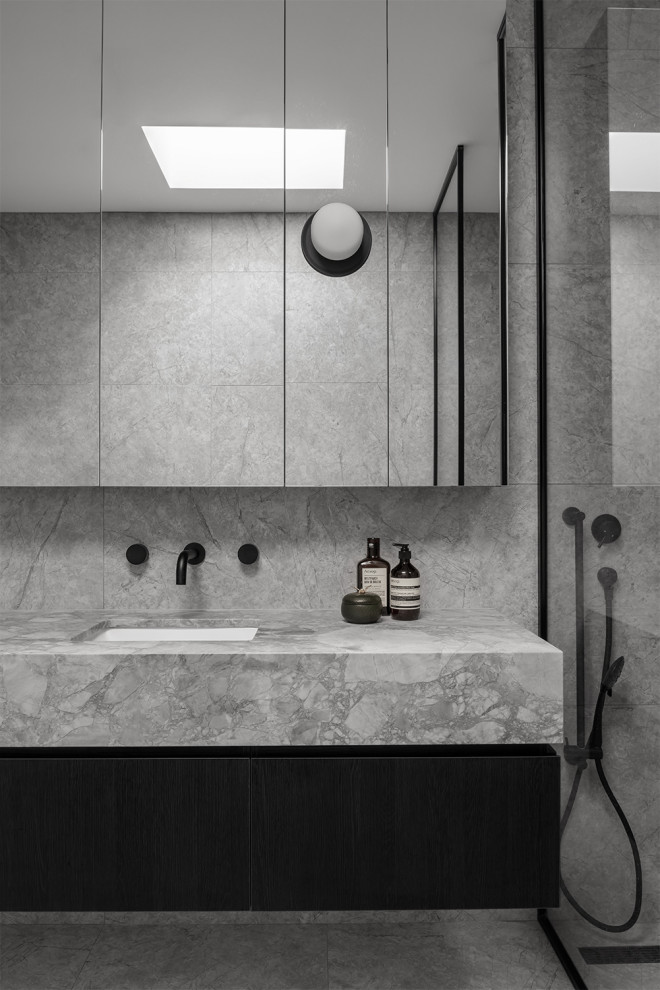 Bild på ett mellanstort funkis grå grått en-suite badrum, med ett fristående badkar, en dubbeldusch, en toalettstol med hel cisternkåpa, grå kakel, stenkakel, grå väggar, marmorgolv, ett undermonterad handfat, marmorbänkskiva, grått golv och med dusch som är öppen