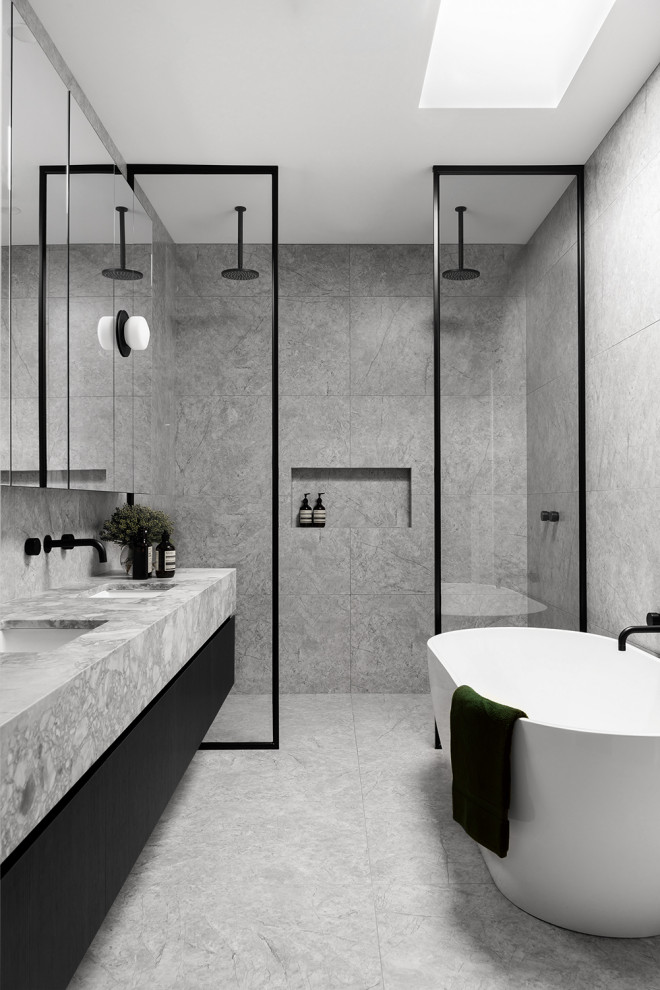 Inredning av ett modernt mellanstort grå grått en-suite badrum, med grå skåp, ett fristående badkar, en dubbeldusch, en toalettstol med hel cisternkåpa, grå kakel, stenkakel, grå väggar, marmorgolv, ett undermonterad handfat, marmorbänkskiva, grått golv och med dusch som är öppen