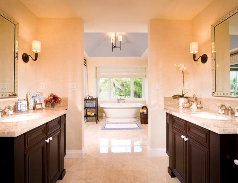 Foto di una stanza da bagno tropicale con lavabo sottopiano, ante con riquadro incassato, ante in legno bruno, top in granito, vasca freestanding, piastrelle beige, pareti beige e pavimento in travertino
