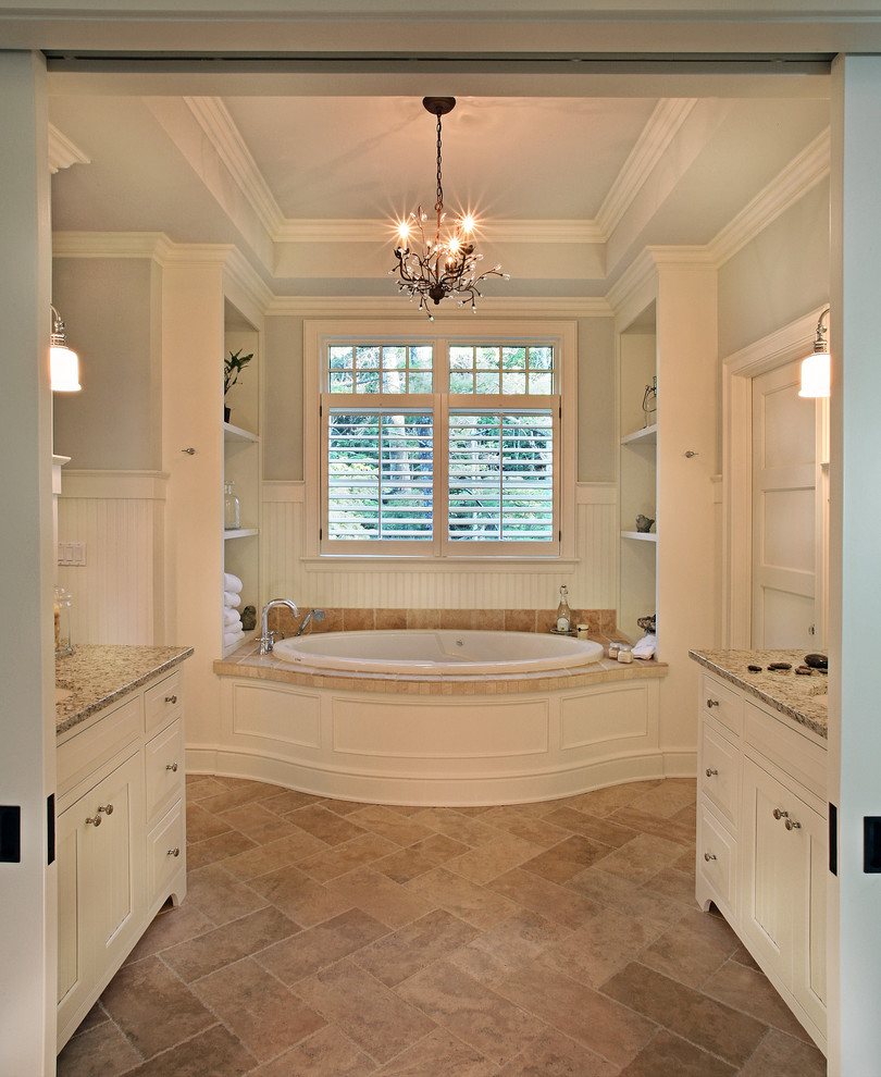 Example of a large trendy master drop-in bathtub design in Grand Rapids with recessed-panel cabinets, white cabinets, beige walls, an undermount sink and granite countertops