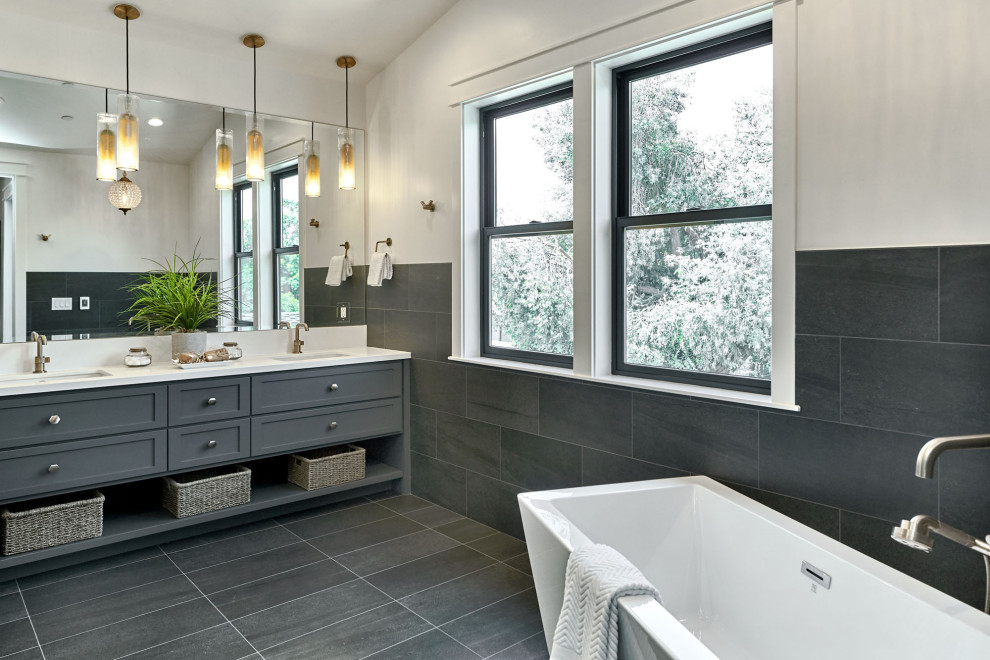 Aménagement d'une salle de bain classique avec un placard à porte shaker, des portes de placard grises, une baignoire indépendante, un carrelage gris, un mur blanc, un lavabo encastré, un sol gris, un plan de toilette blanc et meuble double vasque.