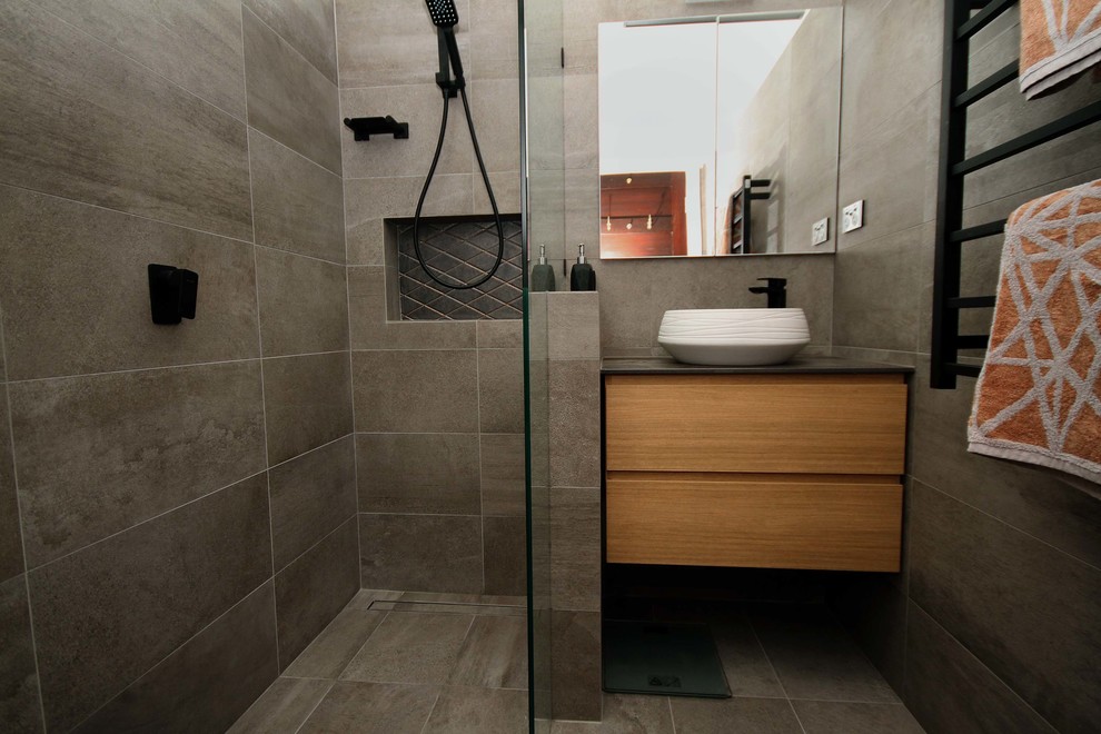 Imagen de cuarto de baño urbano pequeño con ducha abierta, sanitario de una pieza, baldosas y/o azulejos grises, baldosas y/o azulejos de porcelana, suelo de baldosas de porcelana, lavabo sobreencimera, suelo gris y ducha abierta